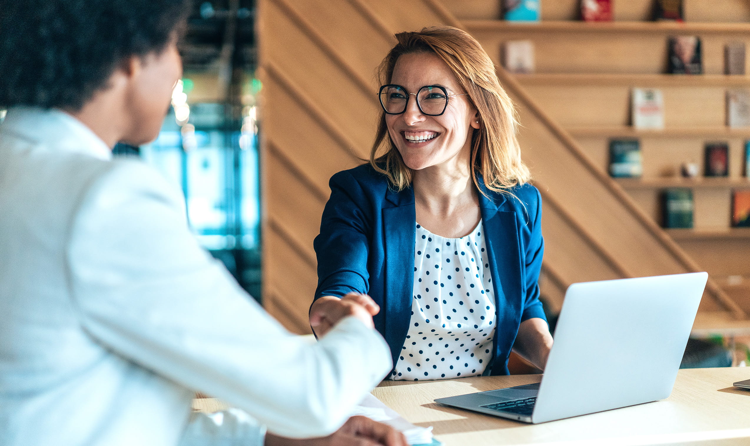 Woman in blue jacket shaking hands with another woman
