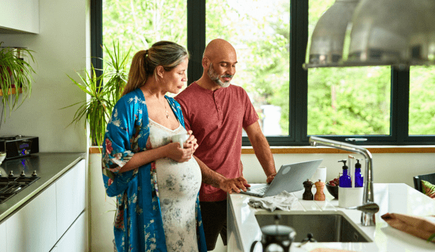 Couple expecting child review information on a computer