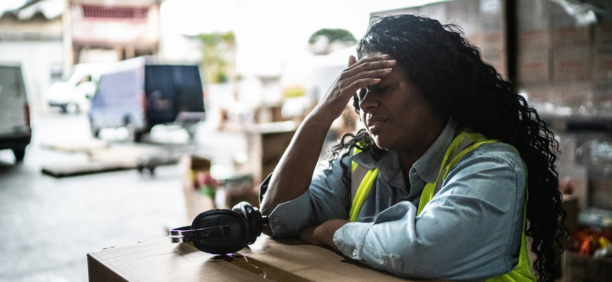 Stressed warehouse worker with her hands to her forehead.