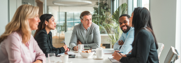Five employees sitting around a conference table