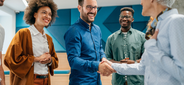 New hire shaking hands and meeting smiling coworkers.
