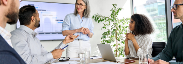 Female leader talking to employees in a conference room. 