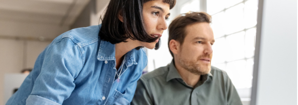 Male and female employees looking at a computer together. 