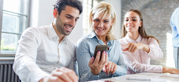 three employees looking at smartphone and smiling