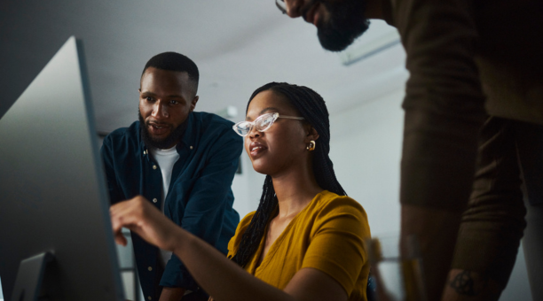 Three employees looking at a laptop.